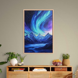 May include: A framed landscape painting depicts a mountain range under a swirling aurora borealis. The artwork features shades of blue, purple, and white, with a light-colored wooden frame. The painting evokes a sense of natural beauty and celestial wonder.