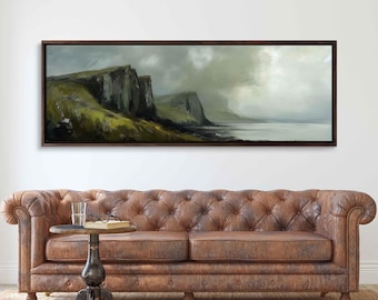 May include: A panoramic landscape painting depicting a rocky coastline with green hills and a cloudy sky. The painting is framed in a dark wood frame and hangs on a white wall above a brown leather sofa.