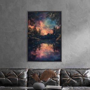May include: A framed art print depicts a serene lake scene reflecting a vibrant, colorful sky. The artwork features a dark, forested shoreline and a starry night sky with hues of orange, blue, and purple. The print is displayed on a gray wall above a black leather couch.