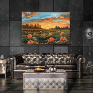 May include: A painting of a field of pumpkins at sunset. The pumpkins are orange and green, and the sky is a mix of orange, pink, and blue. The painting is framed in a dark wood frame.