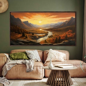May include: A framed landscape painting depicting a winding river flowing through a valley with mountains in the background. The sky is a vibrant orange and yellow, suggesting a sunset.