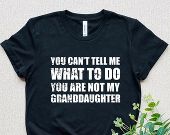 May include: Black t-shirt with white text that reads "You can't tell me what to do you are not my granddaughter".