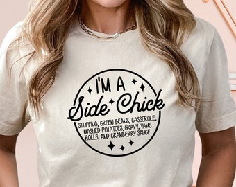May include: A beige t-shirt with a black circle graphic that says "I'm a Side Chick" with a list of side dishes underneath.
