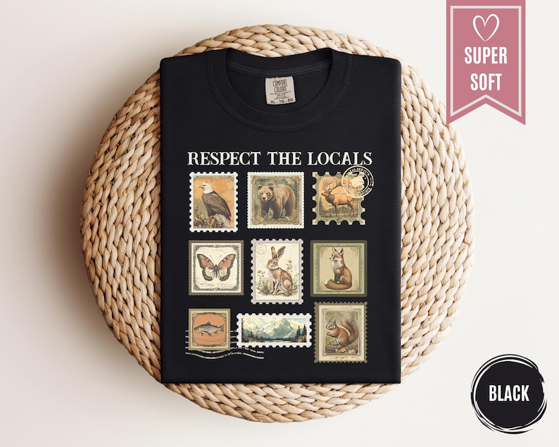 May include: Black t-shirt with the phrase "RESPECT THE LOCALS" and vintage-style postage stamp graphics of various animals. The stamps include an eagle, bear, deer, butterfly, rabbit, fox, fish, mountain scene, and squirrel.