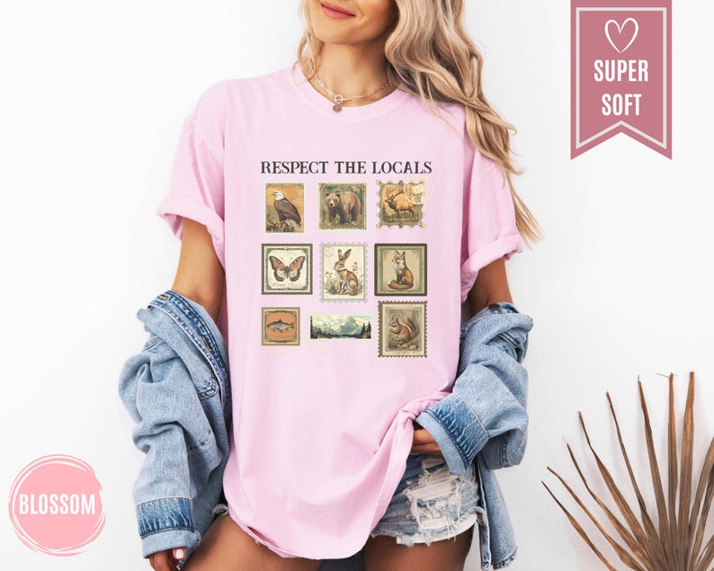 May include: A light pink t-shirt with the text "RESPECT THE LOCALS" and a collection of vintage-style postage stamp illustrations featuring various animals and landscapes. The shirt is made of a soft material.