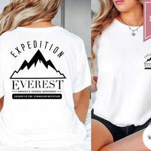 Op de afbeelding: Wit T-shirt met een zwarte bergketenafbeelding en de woorden "EXPEDITION EVEREST" en "DISNEY'S ANIMAL KINGDOM". De tekst "LEGEND OF THE FORBIDDEN MOUNTAIN" is ook aanwezig. Het shirt is gelabeld met "SUPER SOFT" en "WHITE".