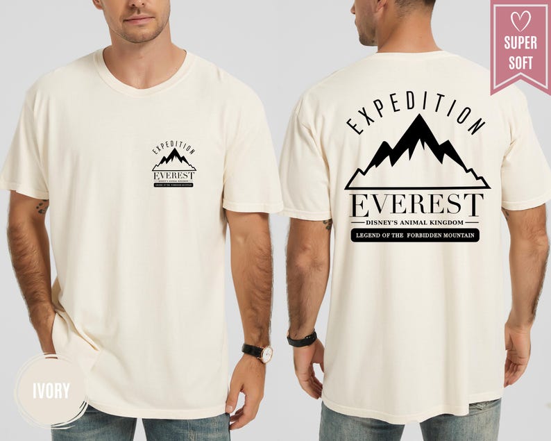 Op de afbeelding: Ivoor kleurig t-shirt met een zwarte afbeelding van een bergketen en het woord "EVEREST". De achterkant van het shirt heeft de tekst "EXPEDITION" boven de bergafbeelding, met "DISNEY'S ANIMAL KINGDOM" en "LEGEND OF THE FORBIDDEN MOUNTAIN" eronder.