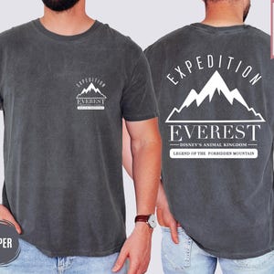 Op de afbeelding: Donkergrijze t-shirt met een witte berg afbeelding en de tekst "EXPEDITION EVEREST" op de voorkant. De achterkant van de shirt heeft een grotere berg afbeelding en de tekst "EXPEDITION EVEREST - DISNEY'S ANIMAL KINGDOM - LEGEND OF THE FORBIDDEN MOUNTAIN."