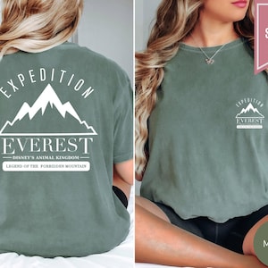Op de afbeelding: Mosgroen t-shirt met witte grafische tekst en bergontwerp. De voorkant van het shirt heeft een kleine bergafbeelding en de tekst "Expedition Everest". De achterkant van het shirt heeft een grotere bergafbeelding en de tekst "Expedition Everest - Disney's Animal Kingdom - Legend of the Forbidden Mountain".