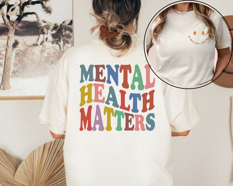 May include: A white t-shirt with the text "MENTAL HEALTH MATTERS" in rainbow colors on the back. The front of the shirt has the text "Be Kind To Your Mind" with a smiley face.
