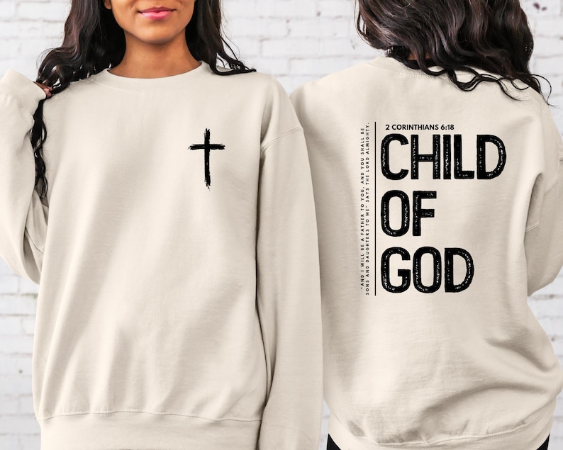 May include: A beige sweatshirt with a black cross on the front and the text "CHILD OF GOD" and the Bible verse "2 Corinthians 6:18" on the back.