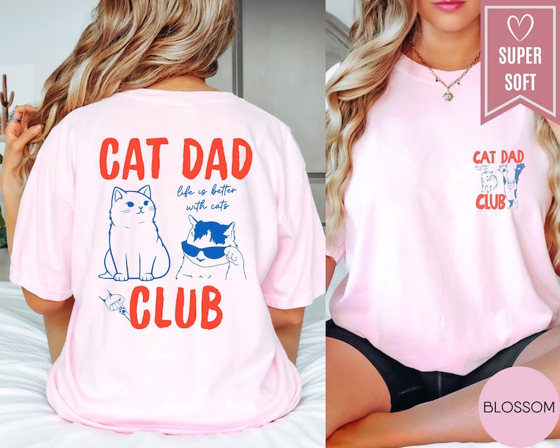May include: A light pink t-shirt with the words "CAT DAD CLUB" in red. The back of the shirt features two cat illustrations and the phrase "life is better with cats." The front has a smaller "CAT DAD CLUB" design.