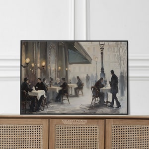 May include: A vintage painting of a Parisian cafe scene with people sitting at tables outside. The cafe has a green awning and is lit by gas lamps. The painting is in a black frame.