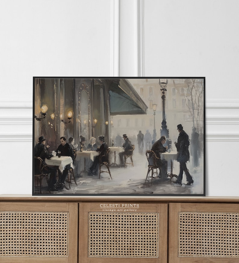 May include: A vintage painting of a Parisian cafe scene with people sitting at tables outside. The cafe has a green awning and is lit by gas lamps. The painting is in a black frame.