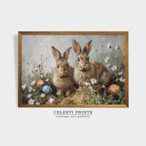 May include: Two brown rabbits sitting in a field of white flowers with colorful Easter eggs. The rabbits are looking at the viewer. The image is framed in a brown wood frame. CELESTI PRINTS vintage art gallery.