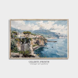 May include: A painting of a coastal town with white buildings on a cliff overlooking a blue sea. The sky is a light blue with white clouds. The painting is framed in a light wood frame.