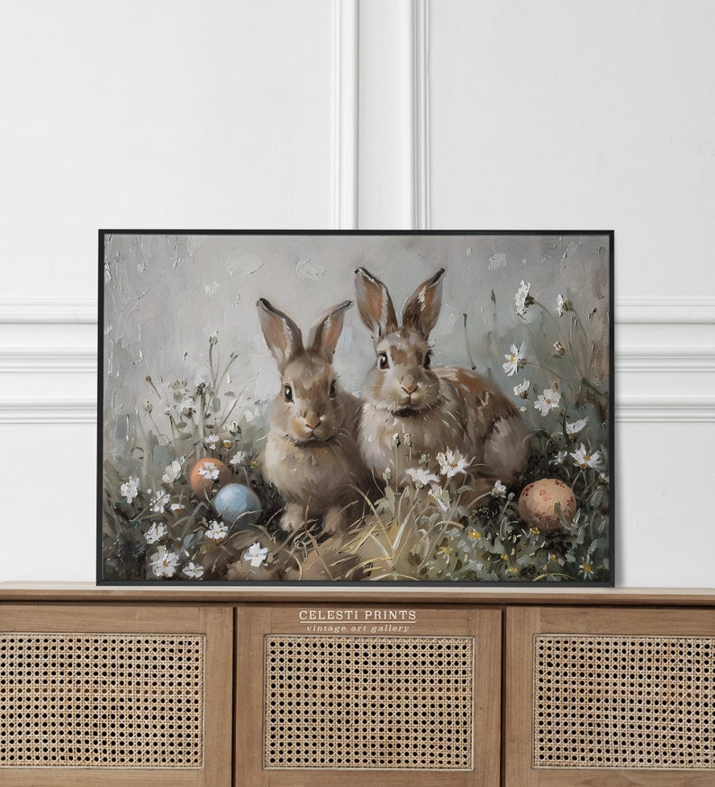 May include: Two brown rabbits sitting in a field of white flowers with blue and orange Easter eggs. The painting is in a black frame and has the text "Celesti Prints vintage art gallery" at the bottom.