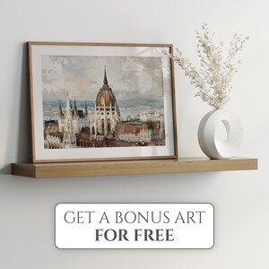 Puede incluir: Una pintura de acuarela enmarcada del edificio del Parlamento h&uacute;ngaro en Budapest. La pintura est&aacute; en un marco de madera claro y se exhibe en un estante de madera con un jarr&oacute;n blanco y flores blancas secas.