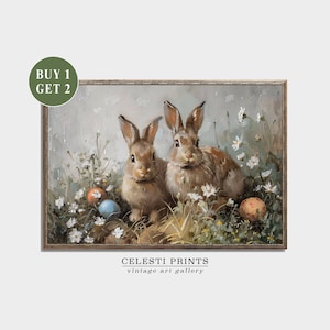 May include: Two brown rabbits sitting in a field of white flowers with colorful Easter eggs. The painting is framed in gold.