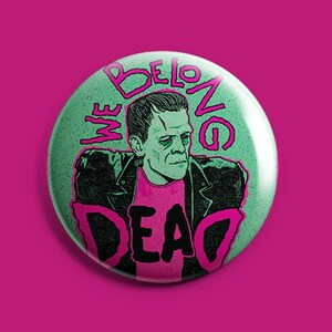 Puede incluir: Un botón verde con un gráfico rosa y negro de Frankenstein con una chaqueta de cuero y una camisa rosa con el texto "We Belong Dead".