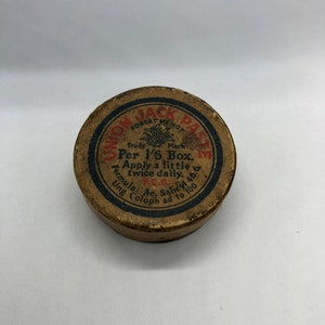 May include: A round, brown cardboard container with a red and black label that reads "Union Jack Paste Forget Me Not Trade Mark Per 1/6 Box. Apply a little twice daily. Formula: Ac. Salicyl 46 Ung Coloph ad to 100."