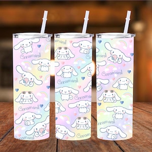 May include: Three stainless steel tumblers with a rainbow ombre design and a repeating pattern of a cartoon dog with the text "Cinnamoroll" on each tumbler. Each tumbler has a clear lid and a straw.