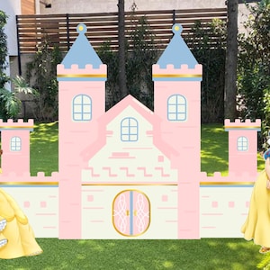 May include: A pink and blue cardboard castle with four princesses: Cinderella, Belle, Snow White, and Aurora. The castle has two towers with blue roofs and gold accents. The princesses are in their iconic gowns, standing on a green lawn.