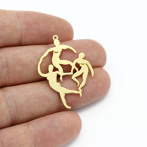 Puede incluir: Encanto de metal dorado con un diseño recortado de tres figuras en formación circular.