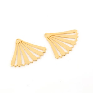 May include: Two gold metal fan-shaped embellishments with a scalloped edge.