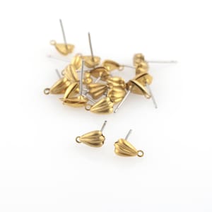 Peut inclure: Gros plan sur un tas de fermoirs de boucles d'oreilles de couleur dorée à bord festonné. Les fermoirs sont en métal et ont une petite boucle en haut pour attacher les boucles d'oreilles.