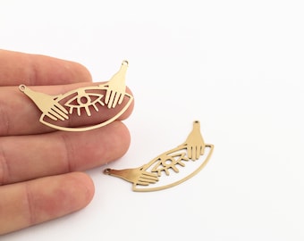 May include: Two gold-toned metal charms shaped like an eye with hands on either side. The charms have a hole at the top for attaching to jewellery.