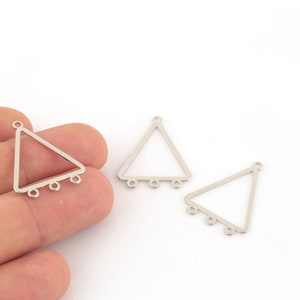 Puede incluir: Tres hallazgos de pendientes de metal de forma triangular plateada con anillas de salto en el borde inferior.