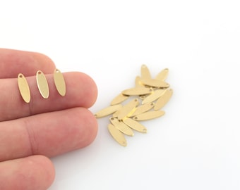 May include: A collection of small, gold-colored oval charms with a hole at the top for jewelry making. The charms are approximately 0.75 inches long and have a smooth, polished surface. Several charms are scattered on a white background.