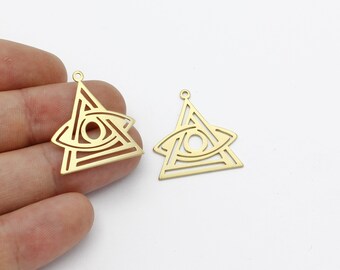 Peut inclure: Deux breloques en métal de couleur dorée en forme de triangle avec un motif d'œil à l'intérieur. L'œil est délimité par une fine ligne et a un petit cercle au centre.