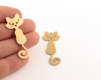 Puede incluir: Dos abalorios de metal dorado en forma de gato con cola enroscada. Los gatos tienen un diseño simple y de dibujos animados con ojos y nariz.