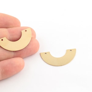 May include: Two gold-colored metal half-circle shapes with two holes each. The shapes are flat and have a smooth surface.