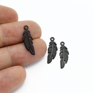 May include: Three black metal feather charms with a loop at the top for attaching to jewellery or other crafts.