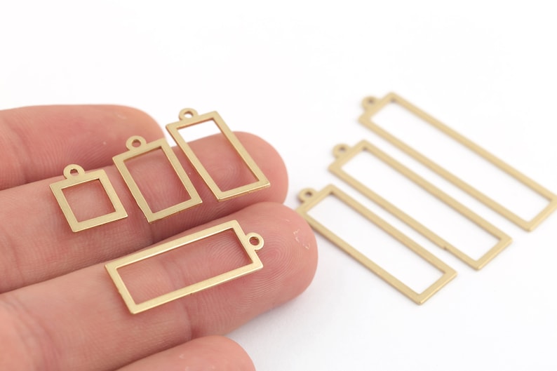 Pode incluir: Um conjunto de seis pingentes de moldura de metal dourado em v&aacute;rios tamanhos. Os pingentes s&atilde;o de forma retangular e quadrada com um pequeno la&ccedil;o na parte superior para prender a joias ou outros artesanatos.