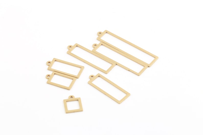 Pode incluir: Um conjunto de seis pingentes de moldura de metal dourado, incluindo cinco molduras retangulares e uma moldura quadrada. Os pingentes t&ecirc;m um la&ccedil;o na parte superior para serem presos a joias ou outros artesanatos.