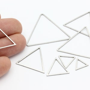 May include: A set of silver triangle-shaped metal charms of various sizes. The charms are made of metal and have a shiny finish.