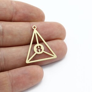May include: Gold-toned metal charm shaped like a triangle with the number 8 inside. The charm has a loop at the top for attaching to a necklace or bracelet.