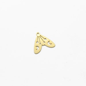 Könnte beinhalten: Goldfarbener Metallanhänger mit einem Halbmond- und Sternendesign. Der Anhänger ist in Form eines Flügelpaares gestaltet.
