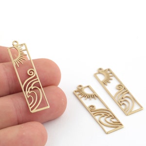 May include: Three gold-colored metal charms with a sun and wave design. The charms are rectangular and have a cutout design.