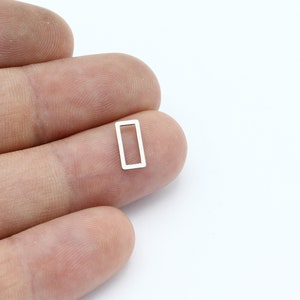 Peut inclure: Un anneau de saut rectangulaire en métal argenté avec une finition lisse.
