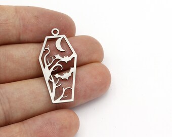 May include: Silver metal charm shaped like a coffin with a crescent moon, tree, and bats cut out.