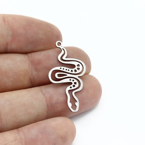 Puede incluir: Encanto de metal plateado en forma de serpiente con un cuerpo enroscado y un diseño detallado. El encanto tiene un anillo de salto en la parte superior para sujetarlo a joyas.