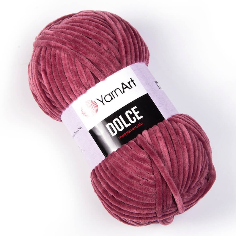 May include: A ball of YarnArt Dolce yarn in a dusty rose color. The yarn has a soft, velvety texture and is wrapped with a label that reads "DOLCE" and "YarnArt". The yarn is ideal for knitting and crochet projects.