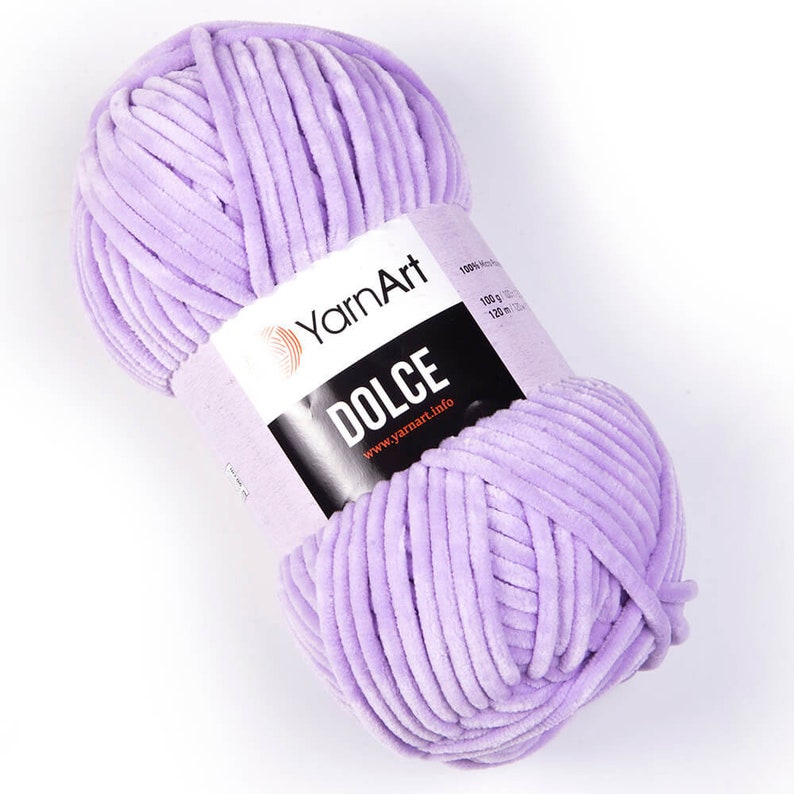May include: A ball of lavender-colored YarnArt Dolce yarn. The label reads "DOLCE" and "www.yarnart.info". The yarn is 100% polyester and weighs 100 g (3.5 oz).