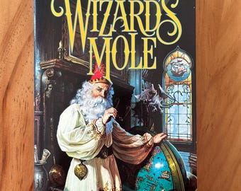 May include: A paperback book titled "Wizard's Mole" by Brad Strickland. The cover features a wizard in a white robe and red hat, holding a globe. The title is in large, ornate yellow letters against a dark background.