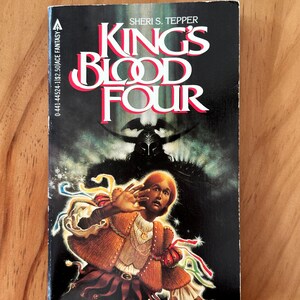 Puede incluir: Un libro de bolsillo titulado "King's Blood Four" de Sheri S. Tepper. La portada presenta un fondo oscuro con una ilustración central de una persona con un atuendo marrón y rojo, con una figura sombría detrás. El libro tiene una cita de Roger Zelazny.